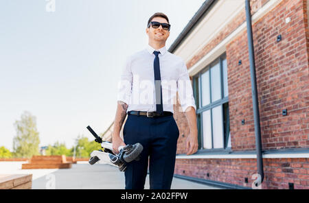 businessman with folding scooter on rooftop Stock Photo