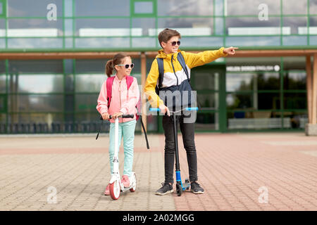 happy school children with backpacks and scooters Stock Photo