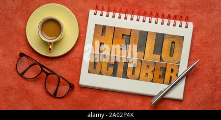 Hello October - letterpress wood type blocks typography in a spiral notebook with a cup of coffee Stock Photo