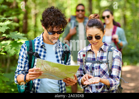 friends with map and backpacks hiking in forest Stock Photo