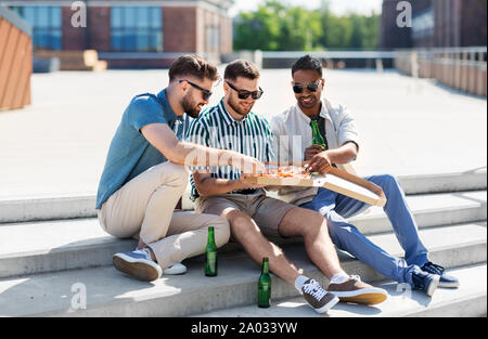 male friends eating pizza with beer on street Stock Photo