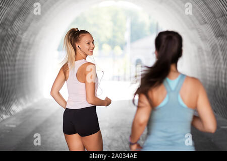women or female friends with earphones running Stock Photo