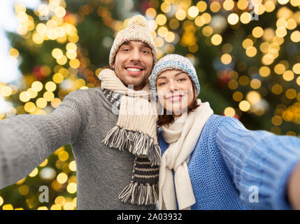 happy couple taking selfie over christmas lights Stock Photo