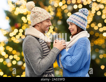 happy couple holding one cup over christmas lights Stock Photo