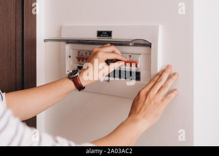 Circuit breaker board displays many switches. A finger is about to turn it back on Stock Photo