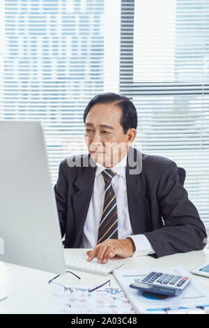 Middle aged Asian businessman feeling stressed and frustrated while working in work station. Business problem concept Stock Photo