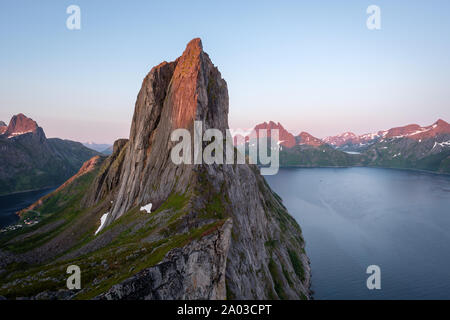 View from Mount Hesten on Iconic Mountain Segla in light of midnightsun with clear sky and mountain range in background, Fjordgard, Senja, Norway