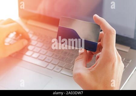Man holding a plastic credit card near the computer close-up. Stock Photo