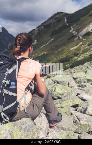 Active life of diabetics, woman hiking and checking glucose level with a remote new technology sensor and mobile phone without blood Stock Photo