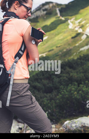 Active life of diabetics, woman hiking and checking glucose level with a remote new technology sensor and mobile phone without blood Stock Photo