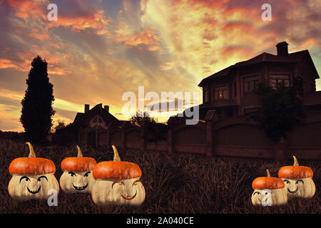 Spooky Halloween pumpkins gather in the grass, background with house and beautiful sunset Stock Photo