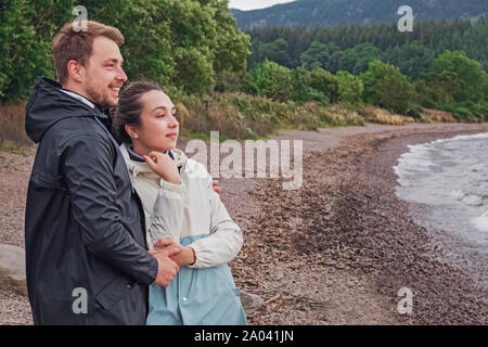 Couple of young tourists standing on the bank of the lake Stock Photo