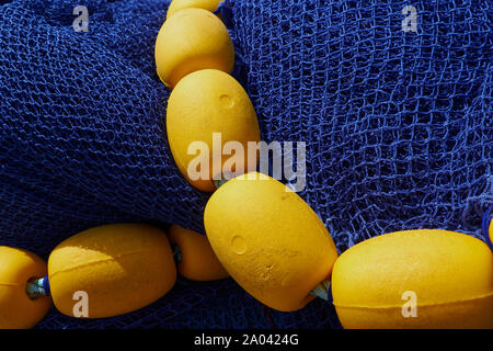 Yellow nylon fishing net with float line attached to small red plastic  floats Stock Photo - Alamy