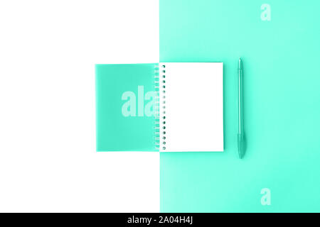 Top view of opened trendy mint cover spiral notepad with pen on mint and white background. Mockup for your design. Flat lay. Stock Photo