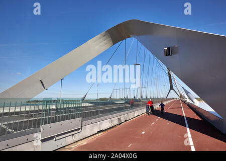 A female and young boy cycling on the bridge deck of a bowstring bridge named De Oversteek which spans the river Waal at Nijmegen Stock Photo