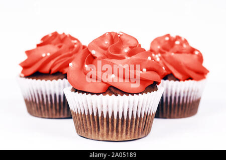 Three delicious cupcakes with icing in trendy coral color on isolated white background. Close-up. Stock Photo