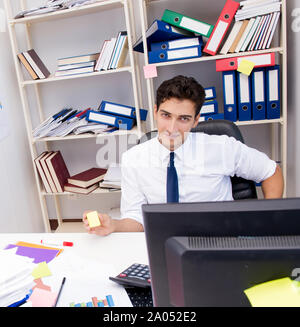 Businessman working in the office with piles of books and papers doing paperwork Stock Photo