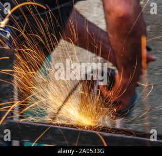 A construction. worker using an angle grinder producing a lot of sparks. close-up. Stock Photo