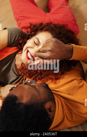 Loving atmosphere. Top view of happy couple that lying on the blanket and laughing at funny joke Stock Photo