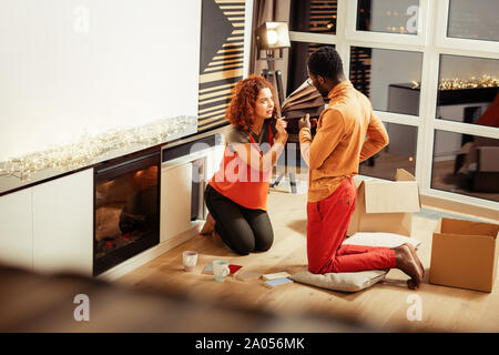 Concentrated international man standing on pillow while consulting with his girlfriend about renovation Stock Photo