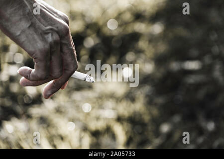 Hand holding a cigarette. A man smoking a cigarette and copy space for insert text. Stock Photo