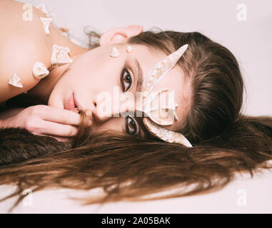 Fairy tale creature with thorns on skin lying on black fur rug. Spirit of nature, tender elf, forest nymph isolated on white background, fantasy Stock Photo
