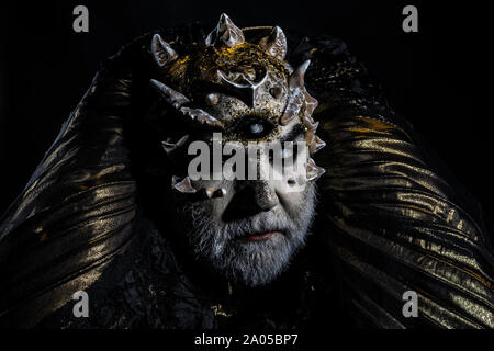 Man with dragon skin and gray beard, alien or reptilian makeup. Monster with sharp thorns and warts. Demon head isolated on black, horror and fantasy Stock Photo