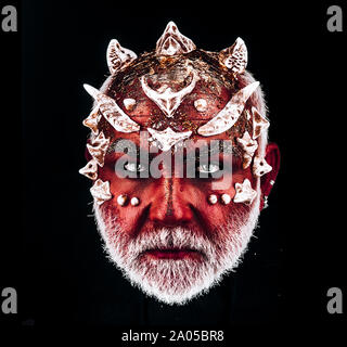 Demon head with evil look. Monster with sharp thorns and warts on face, horror and fantasy concept. Man with white beard and diabolic make-up isolated Stock Photo