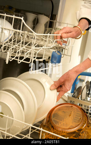 Close-up on the hands of a woman emptying her dishwasher Stock Photo