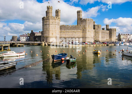 View of Edward 1st 13th century castle reflected in Afon Seiont River at high tide with moored boats. Caernarfon, Gwynedd, Wales, UK, Britain Stock Photo