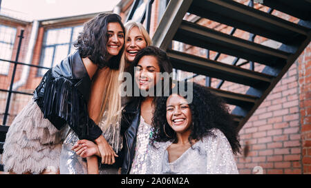 Multi-ethnic group of female friends laughing outdoors standing on the staircase Stock Photo