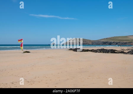 red and yellow safety flags blowing in the wind Constantine Beach, North Cornwall, England, UK Stock Photo