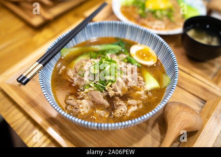 Taichung, Taiwan: A bowl of japanese Ramen Soup with sliced pork and a soft boiled egg on wooden table. Stock Photo