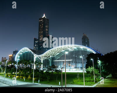 Kaohsiung, Taiwan: Tuntex Sky Tower 85 rising behind the modern Kaohsiung Exhibition Center building at night, late evening. Stock Photo