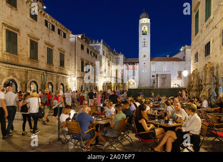 Dubrovnik tourists sitting drinking and eating at a cafe on Stradun at dusk in summer, historical centre, Dubrovnik Croatia Europe Stock Photo