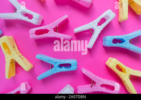 Colored clothespins on a bright pink background. Background, view from the top. Stock Photo
