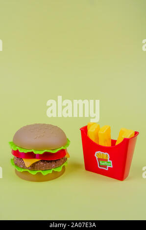 fast food. plastic hamburger and french fries on a yellow background Stock Photo