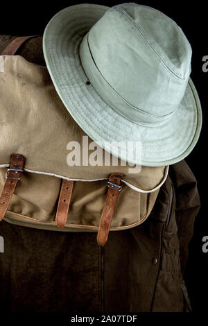 Outdoor coat old game bag and hat on a black background Stock Photo