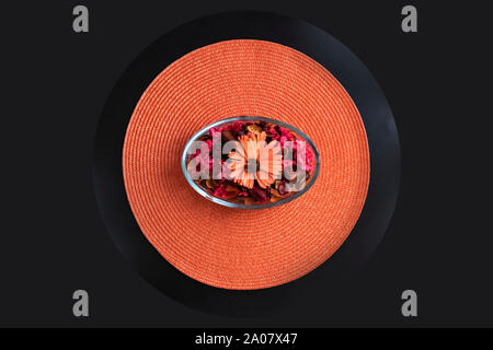 Dried petals flowers It is placed in a decorative bowl.on the orange mat with dark gray background. Stock Photo