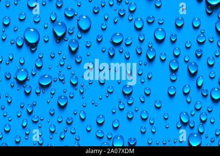 Close up Beaded glistening water droplets on a blue background in a random texture and pattern for a wallpaper Stock Photo