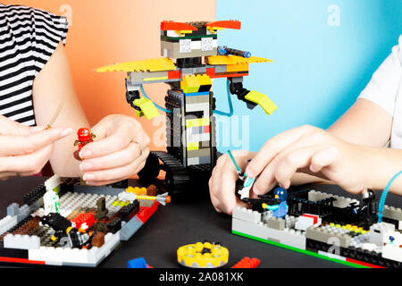 Lego robot. A child and a woman assemble a robot from plastic parts, train. The hottest gadgets. E-learning. Modern training technologies. education Stock Photo