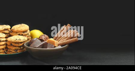 Closeup of chocolate sweets and biscuits / cookies isolated on black with negative space Stock Photo