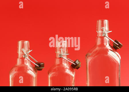 Closeup of three glass empty open bottles over red background Stock Photo