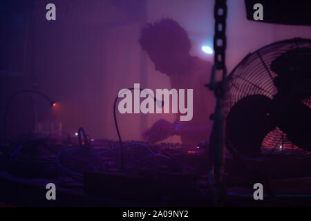 DJ playing vinyl records behind a turn table in a techno night club Stock Photo