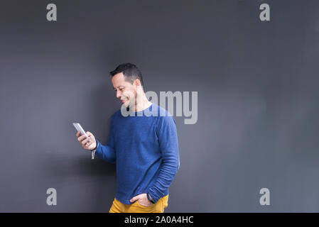 businessman standing at concrete wall looking at cell phone Stock Photo