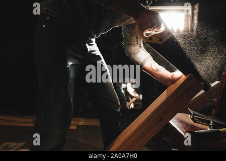 Young Man Saws Wood in Workshop Stock Photo