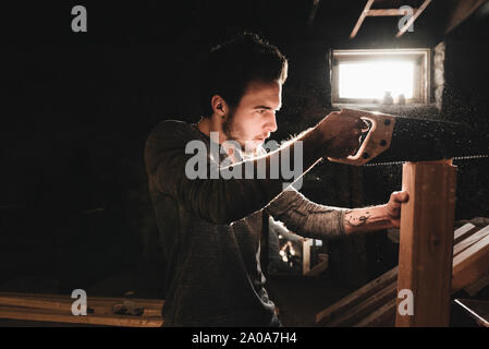 Young Man Saws Wood in Workshop Stock Photo