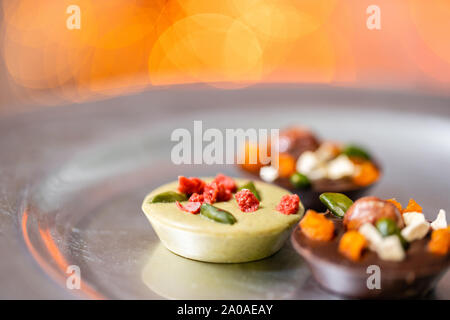 Christmas theme. Handmade chocolates candy. Mini chocolate dessert covered with nuts and dried fruits. Garland lamps bokeh on background. Copy space Stock Photo