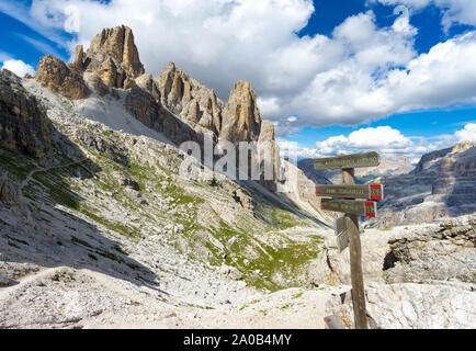 wild and picturesque mountain landscape with wooden trail marker in the foreground in the Italian Dolomites Stock Photo