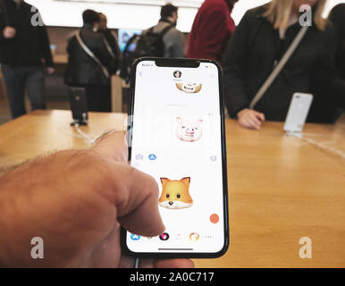 Paris, France - Nov 3, 2017: Customers admiring inside Apple Store the latest professional iPhone smartphone manufactured by Apple Computers looking at available Animoji Stock Photo
